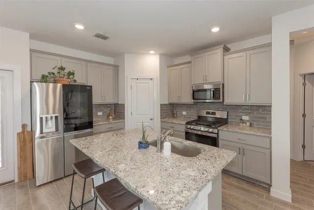 a kitchen with stainless steel appliances granite countertop a sink stove refrigerator and cabinets