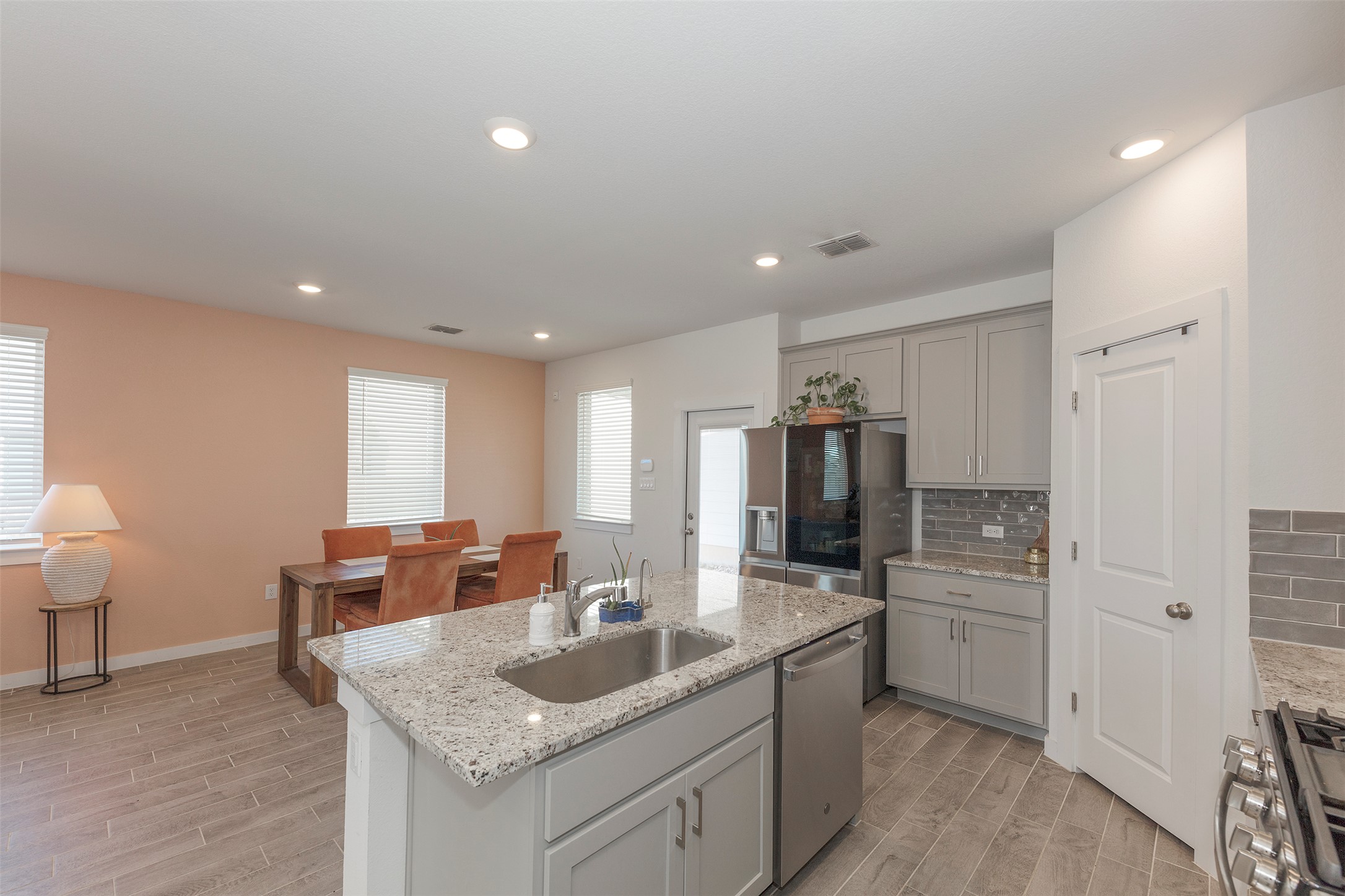 236 Garner Drive Kyle, TX 78640 - Photo 5 of 37 Kitchen featuring gray cabinetry, decorative backsplash, light stone counters, wood finish floors, and recessed lighting