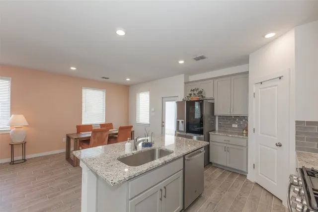 a kitchen with stainless steel appliances granite countertop a sink refrigerator and cabinets