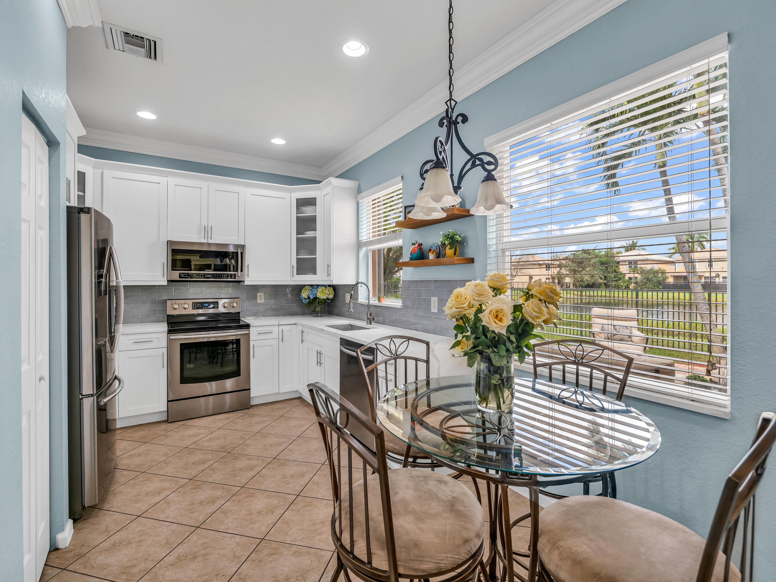 7951 Red Mahogany Road Boynton Beach, FL 33437 - Photo 16 of 33 a kitchen with granite countertop stainless steel appliances a dining table and chairs