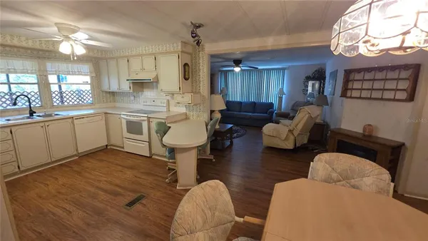 a living room with furniture a rug kitchen view and a large window