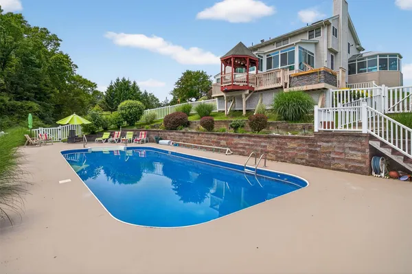 a view of a swimming pool with a lounge chairs in front of a house