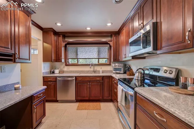 a kitchen with stainless steel appliances granite countertop wooden cabinets a stove top oven a sink and dishwasher