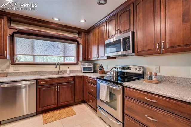 a kitchen with granite countertop wooden cabinets stainless steel appliances and a sink