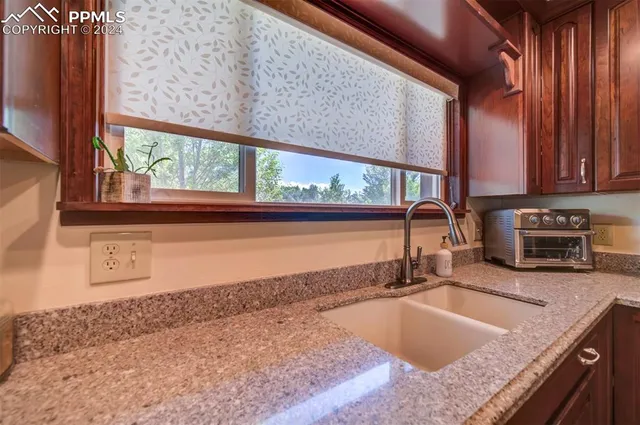 a kitchen with granite countertop a sink a counter top space and cabinets