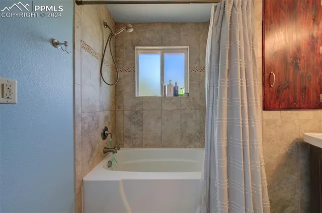 a bathroom with a tub shower and a mirror