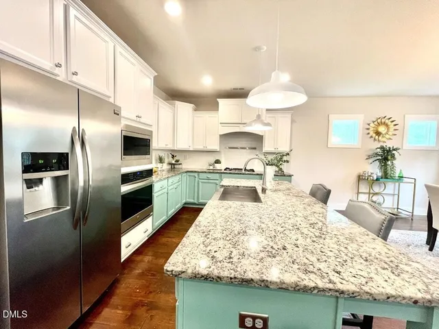 a kitchen with stainless steel appliances granite countertop a stove a sink dishwasher a dining table and chairs with wooden floor