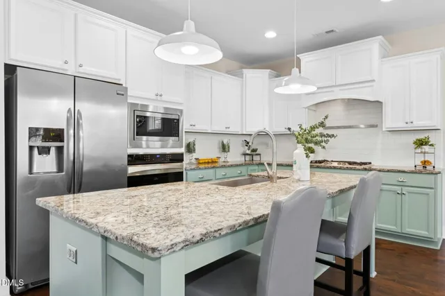 a kitchen with granite countertop a table chairs microwave and refrigerator