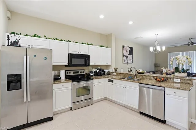 a kitchen with granite countertop a sink stainless steel appliances and white cabinets