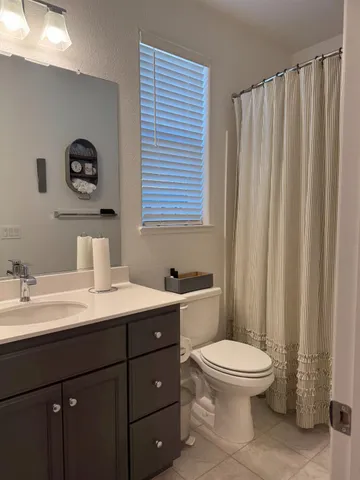 a bathroom with a toilet sink vanity and mirror