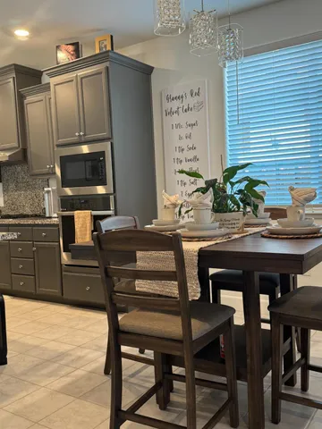 a kitchen with stainless steel appliances kitchen island granite countertop a table chairs and a refrigerator