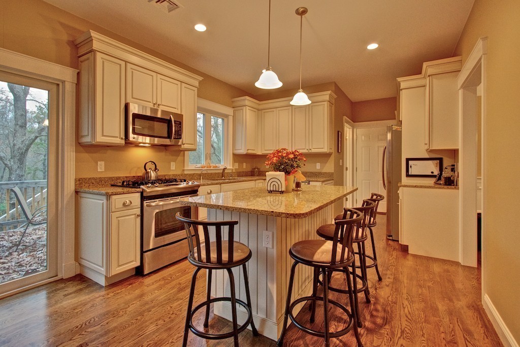 550 Edgell Road Framingham, MA 01701 - Photo 6 of 29 a kitchen with stainless steel appliances kitchen island granite countertop a stove a sink a refrigerator and a dining table with wooden floor