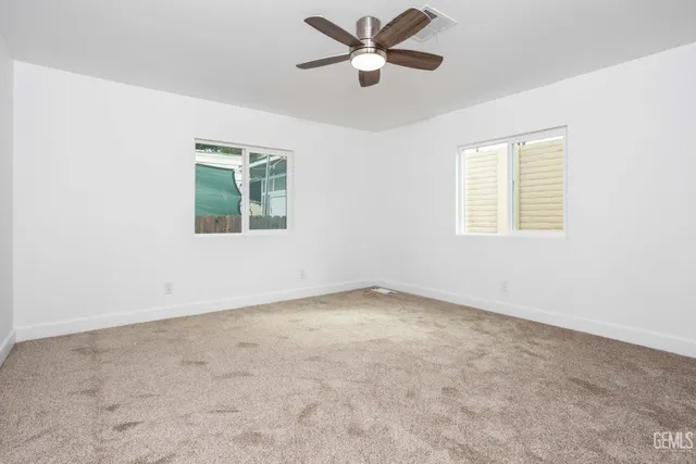 an empty room with a window and a fan