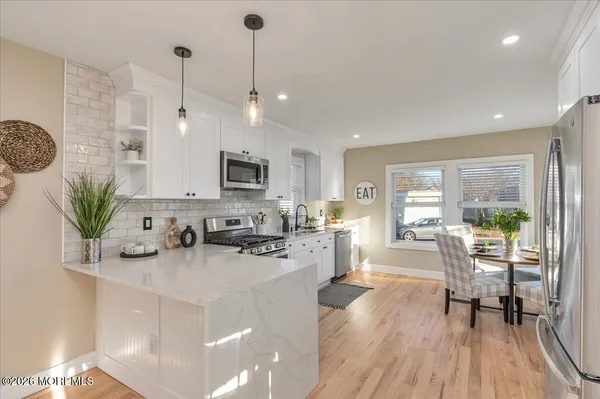 a kitchen with stainless steel appliances a dining table chairs stove a refrigerator and cabinets