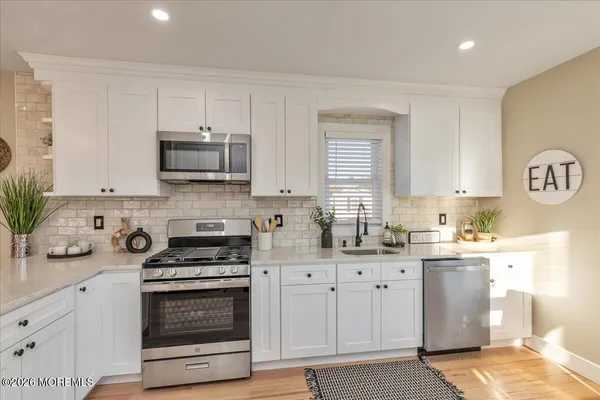 a kitchen with kitchen island granite countertop a sink cabinets and stainless steel appliances