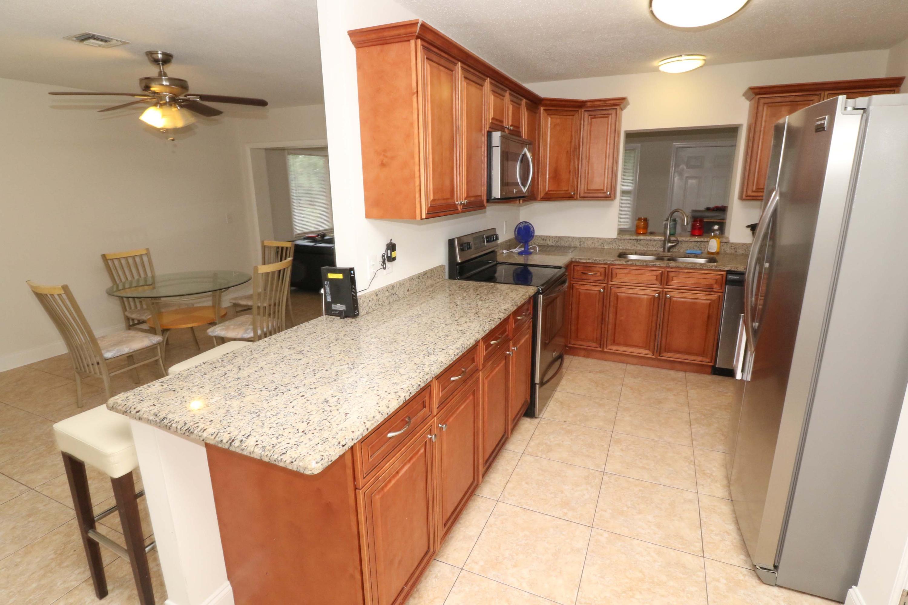 3302 Bermuda Road Palm Beach Gardens, FL 33410 - Photo 3 of 12 a kitchen with stainless steel appliances granite countertop a sink stove and refrigerator