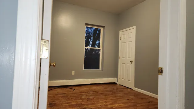a view of an empty room with closet and wooden floor
