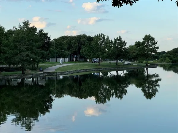 a view of a lake with a yard and large trees