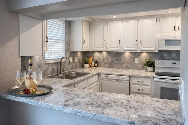a kitchen with granite countertop a sink stainless steel appliances and cabinets