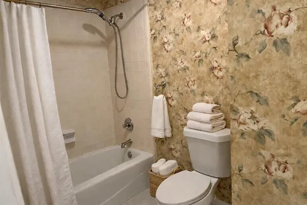a white toilet sitting next to a bath tub and shower curtain