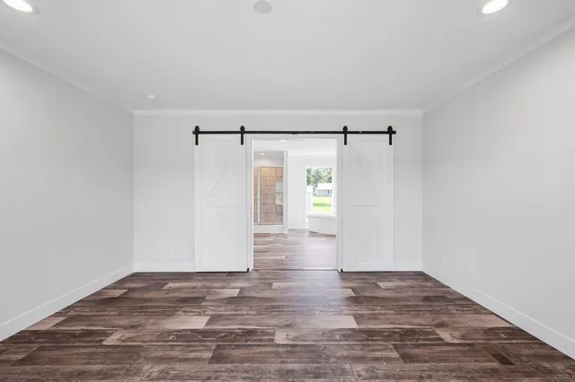 a view of an empty room with wooden floor and a ceiling fan