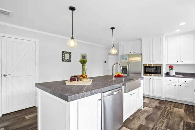 a kitchen with stainless steel appliances granite countertop a sink a stove and a wooden floors