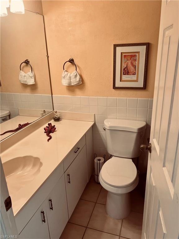 121 Gabriel Circle, Unit 7 Naples, FL 34104 - Photo 17 of 20 Bathroom with toilet, tile patterned flooring, vanity, tasteful backsplash, and tile walls