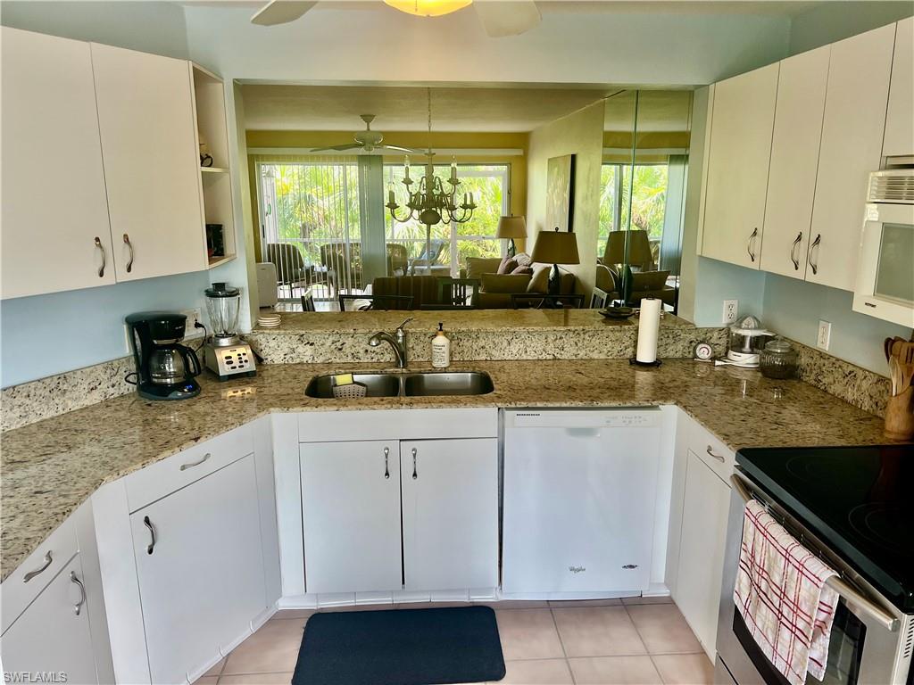 121 Gabriel Circle, Unit 7 Naples, FL 34104 - Photo 5 of 20 Kitchen featuring ceiling fan with notable chandelier, white appliances, white cabinetry, and light stone countertops