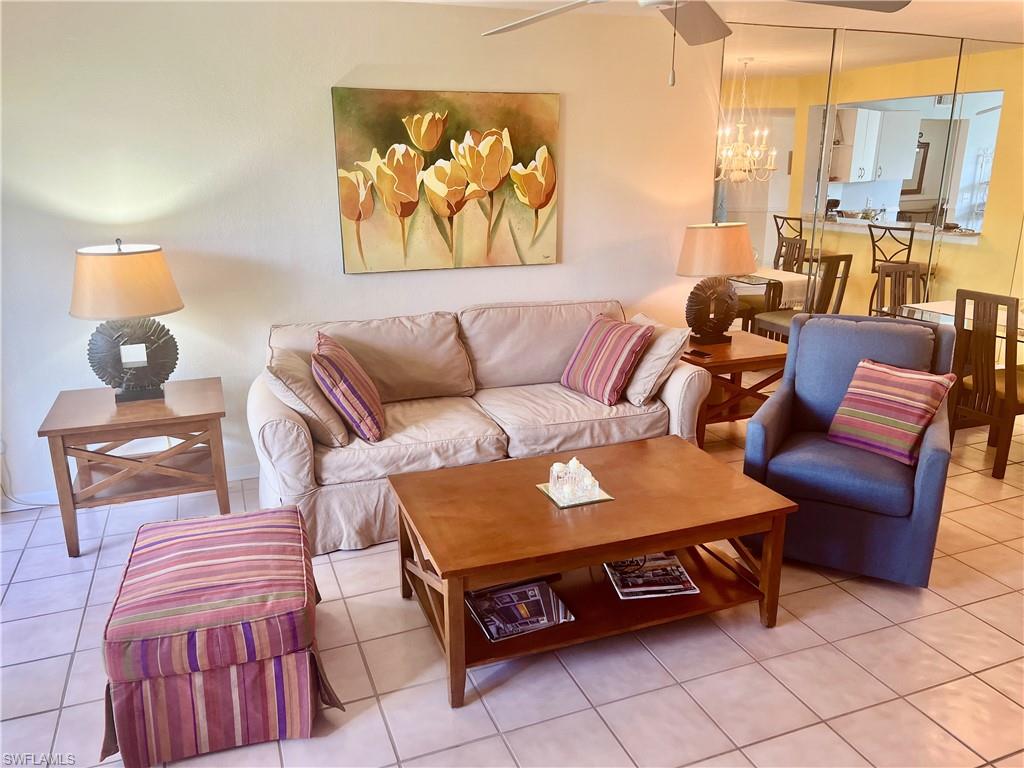 121 Gabriel Circle, Unit 7 Naples, FL 34104 - Photo 6 of 20 Living room featuring an inviting chandelier and tile patterned floors