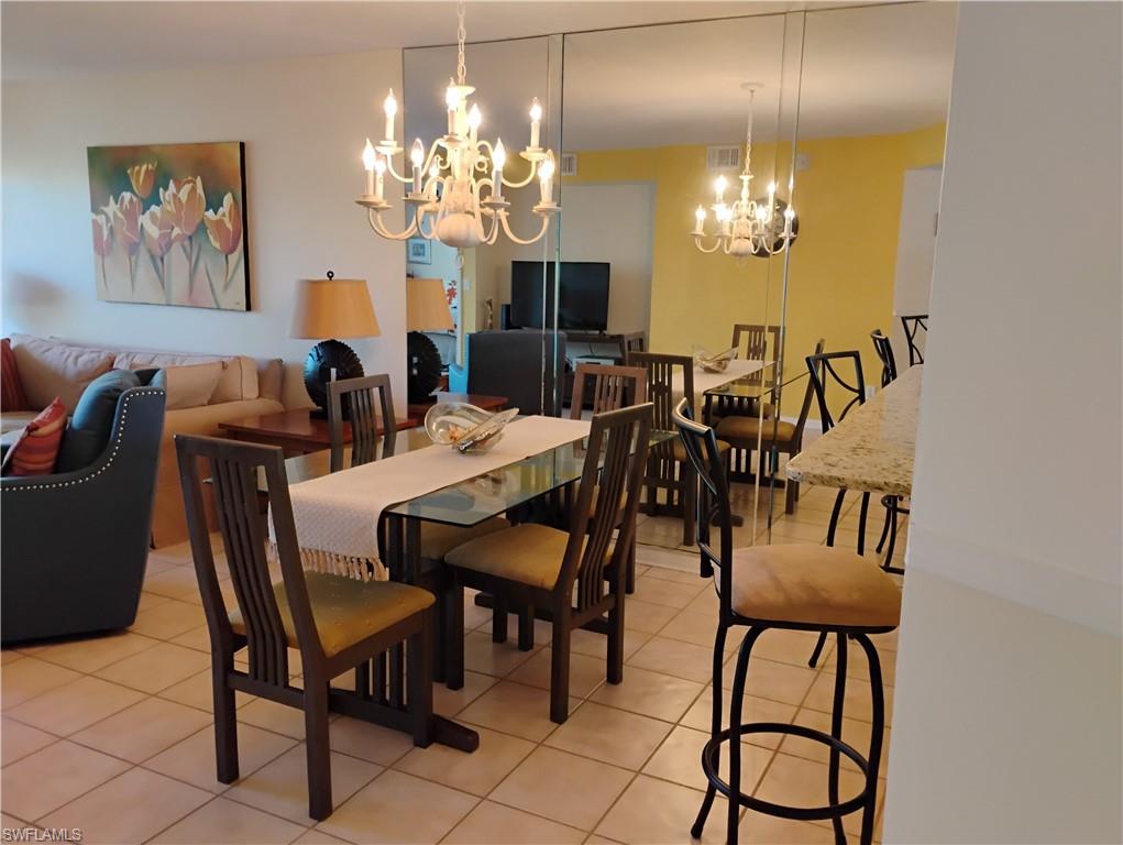 121 Gabriel Circle, Unit 7 Naples, FL 34104 - Photo 9 of 20 Tiled dining space featuring a chandelier