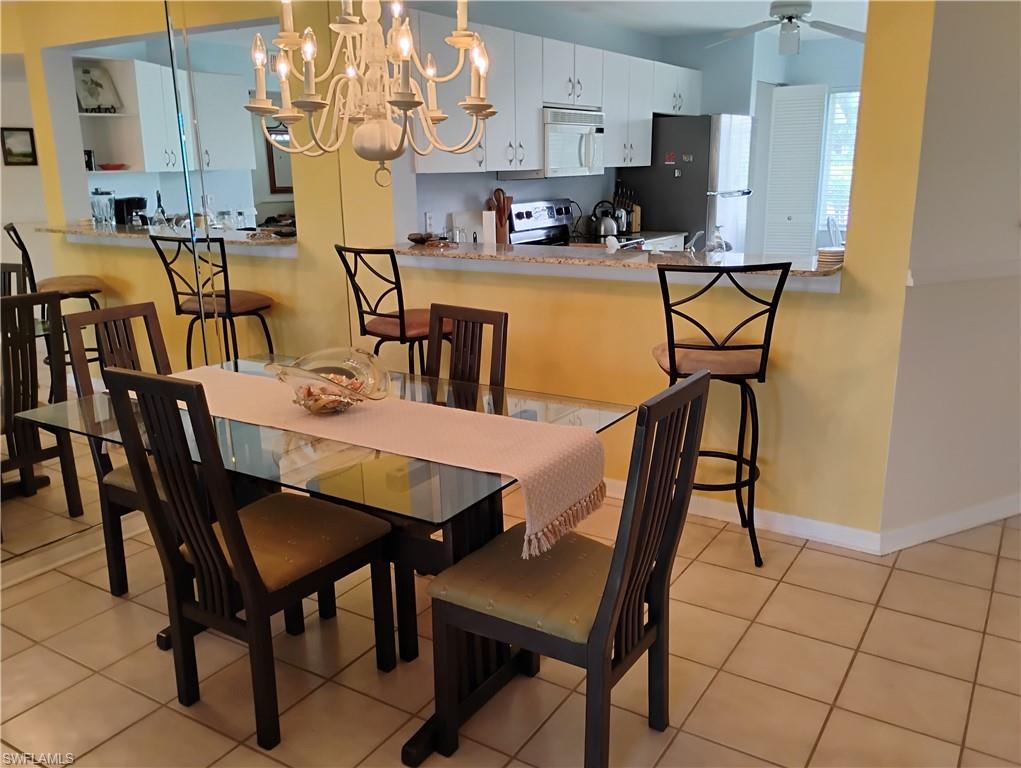 121 Gabriel Circle, Unit 7 Naples, FL 34104 - Photo 10 of 20 Tiled dining area with ceiling fan with notable chandelier