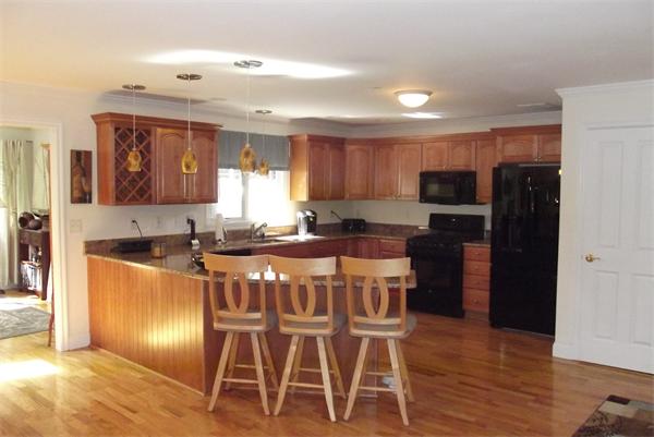 218 Rangeway Road, Unit 283 Billerica, MA 01862 - Photo 3 of 30 a kitchen with kitchen island granite countertop wooden floor cabinets and stainless steel appliances