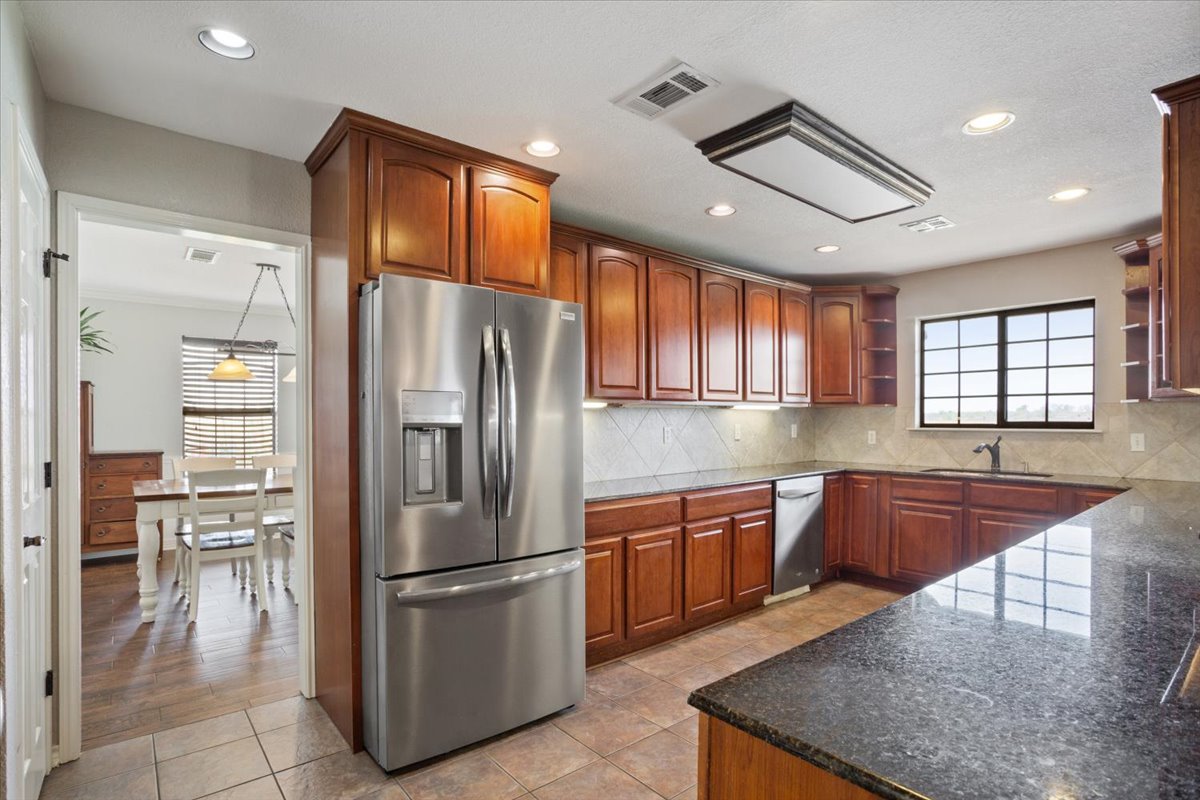 8600 Five Wells Road Rogers, TX 76569 - Photo 11 of 40 Kitchen featuring open shelves, dark stone counters, stainless steel appliances, light tile patterned floors, and recessed lighting
