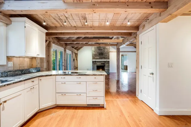a large white kitchen with granite countertop a sink and cabinets