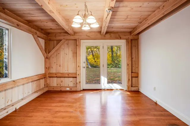 a view of an empty room with wooden floor and windows