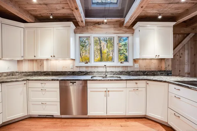 a kitchen with granite countertop white cabinets white appliances a sink and a window