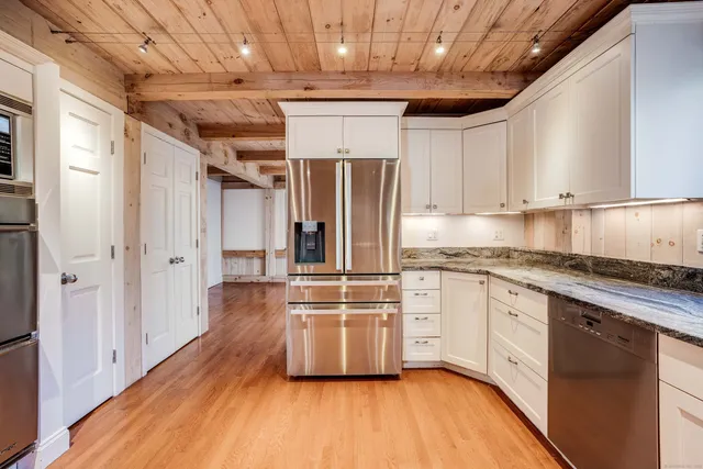 a kitchen with stainless steel appliances a stove a sink and white cabinets with wooden floor