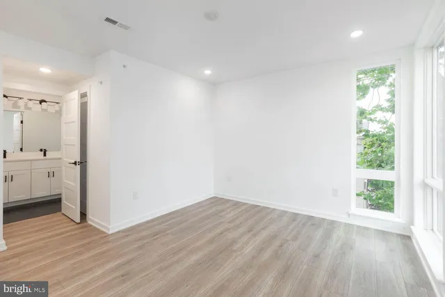 a view of a hallway with wooden floor and a bathroom