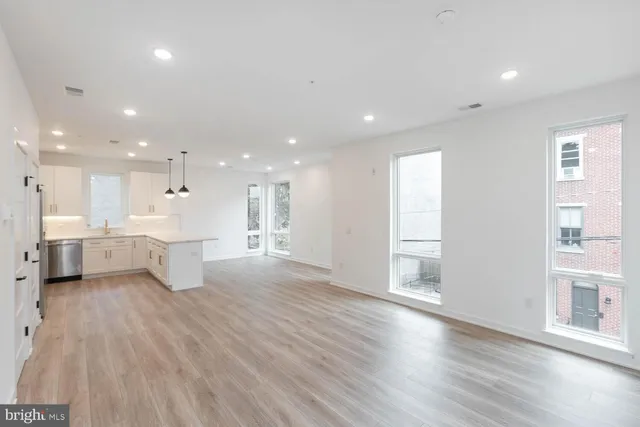 a view of a kitchen with white cabinets and wooden floor