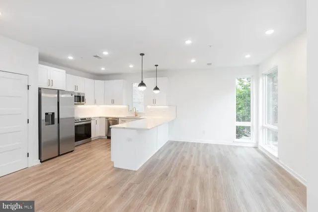 a large kitchen with a large counter top a sink stainless steel appliances and cabinets