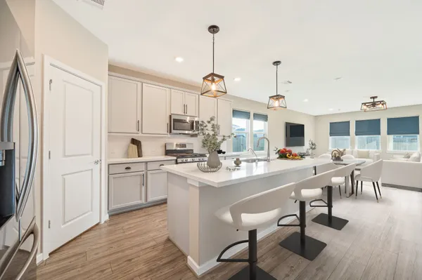 a kitchen with stainless steel appliances kitchen island granite countertop a table chairs and a refrigerator