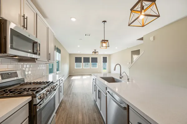 a kitchen with stainless steel appliances granite countertop a sink a stove and a wooden floors