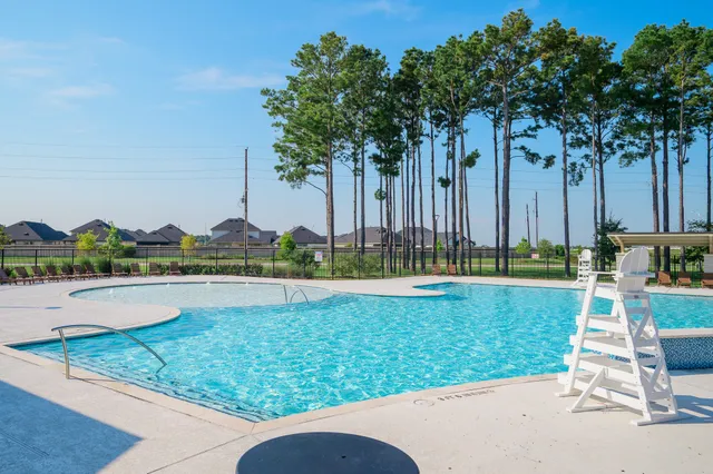 a view of a swimming pool with lawn chairs and a big yard