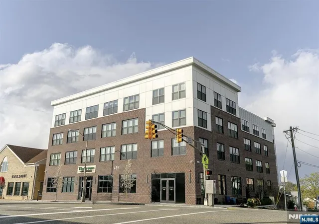 a front view of a building with lot of cars and trees