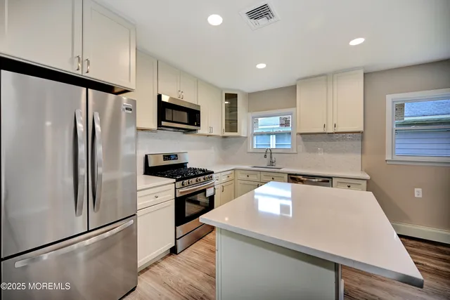 a kitchen with white cabinets and stainless steel appliances