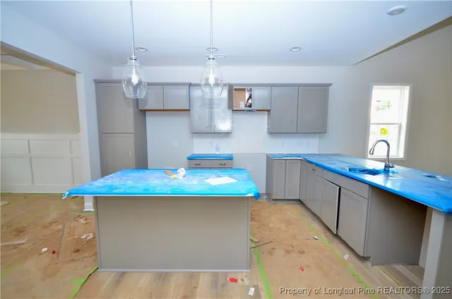 a kitchen with kitchen island granite countertop a sink a counter top space and cabinets