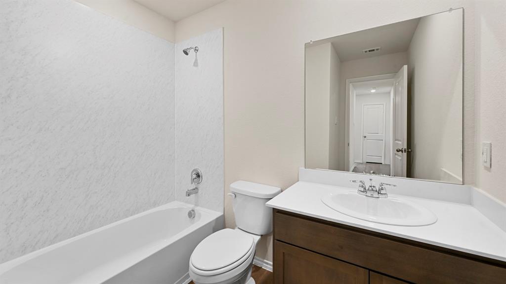 1663 Blaire Drive Tyler, TX 75704 - Photo 25 of 26 Bathroom featuring a white bathtub, shower with chrome fixtures, a toilet, and a vanity with an integrated sink and a large mirror