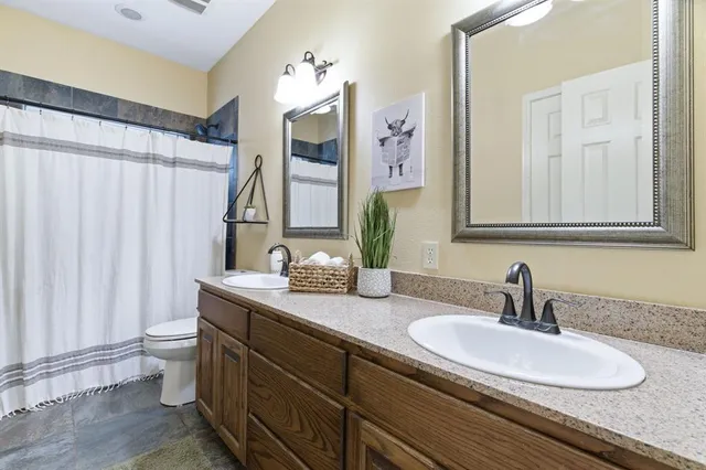 a bathroom with a double vanity sink toilet and a mirror