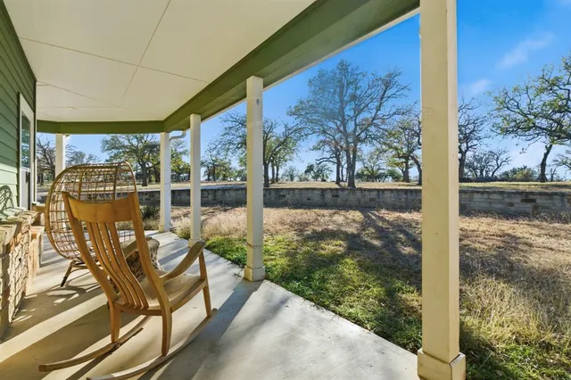a view of a porch with chairs and floor to ceiling window next to a yard