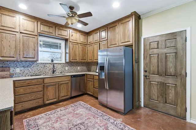 a kitchen with stainless steel appliances granite countertop a refrigerator a sink and white cabinets